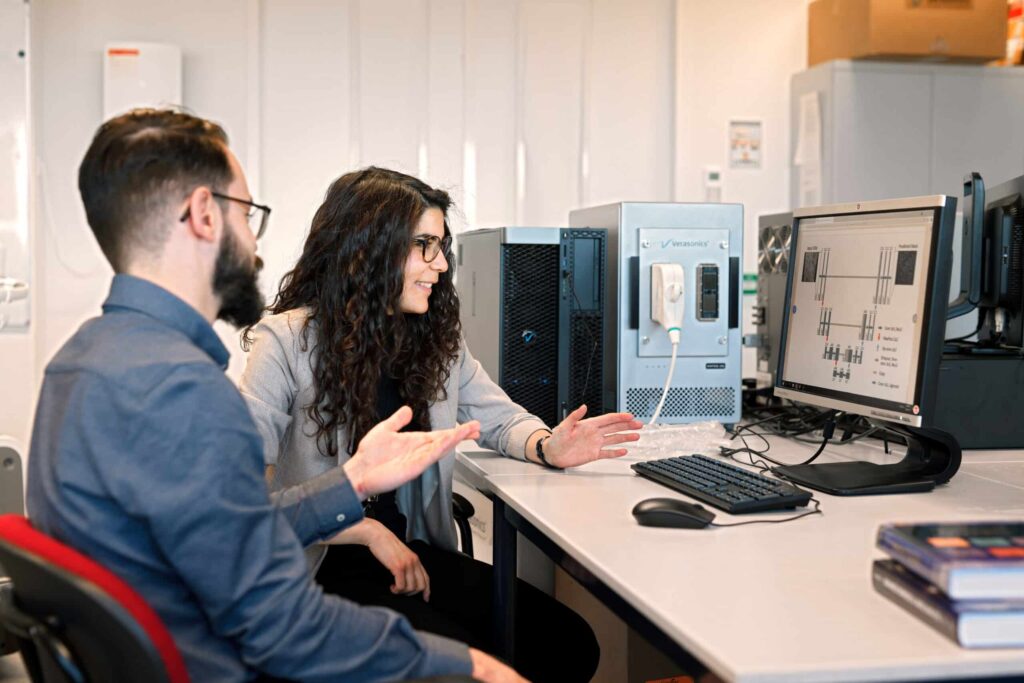 A man and a woman at a desk with laptops in a mentoring session